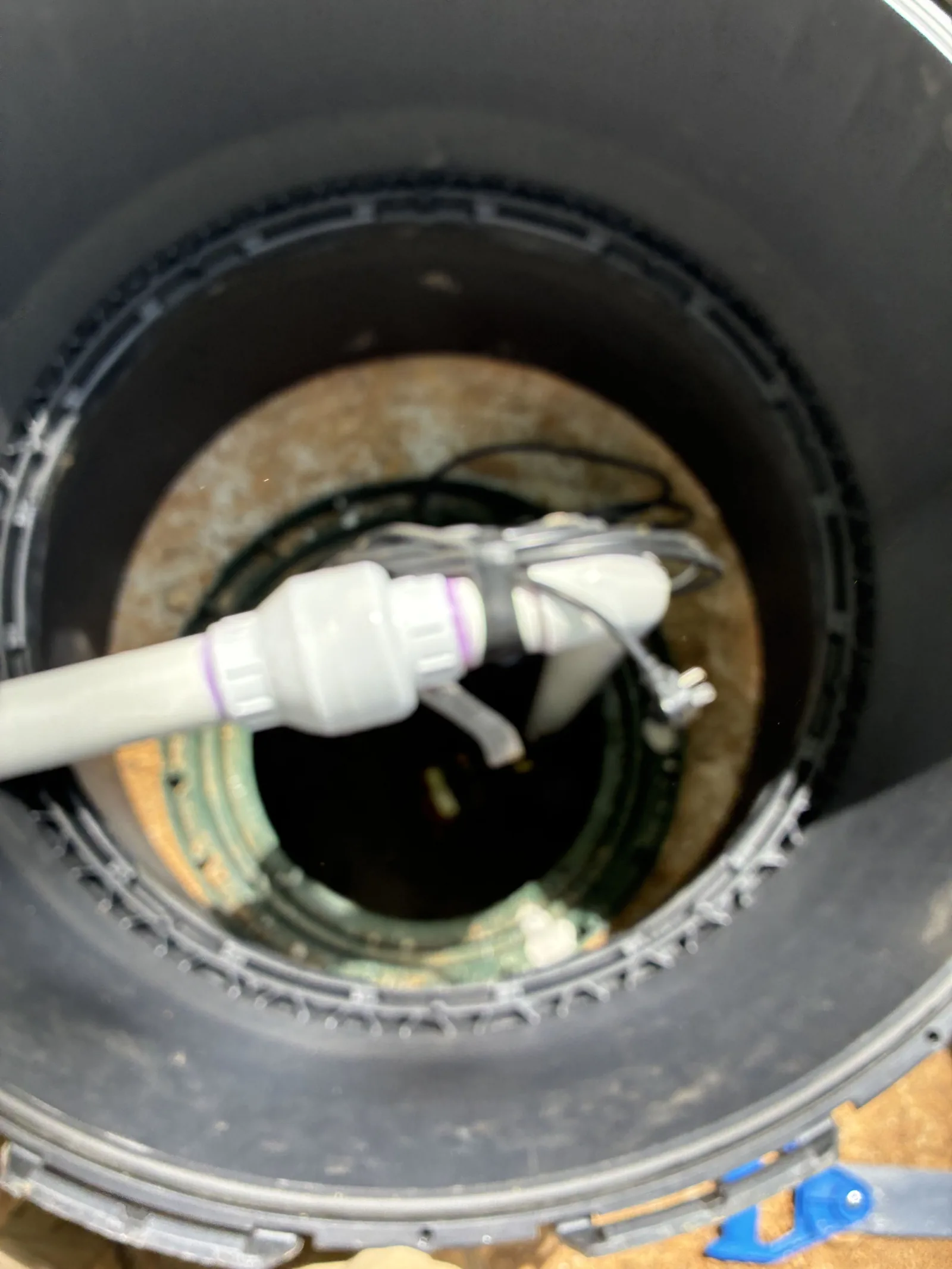 Looking down a plastic septic tank riser at the pump discharge fitting and float cables
